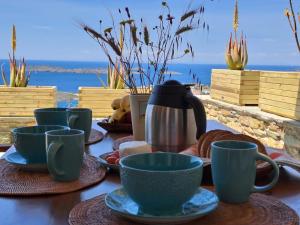 巴特斯欧"Aloe On the Rock", 3-BDR Villa next to Batsi Bay的桌子上摆着杯子和碟子,享有美景