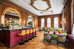 伦敦The Bailey's Hotel London Kensington的餐厅设有酒吧,酒吧设有黄色酒吧凳子