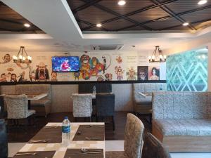 钦奈Hotel Marina Inn Egmore Chennai的一间带桌椅和电视的餐厅