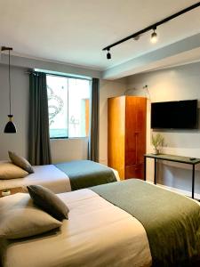 库斯科Casa Encuentro San Blas的酒店客房设有两张床和一台平面电视。