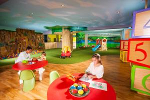 莫雷洛斯港Generations Riviera Maya Family Resort - More Inclusive的坐在游戏室的桌子旁的小女孩