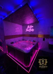 布雷得佛HIGHFIELD PRIVATE SPA APARTMENT的紫色客房 - 带紫色灯浴缸