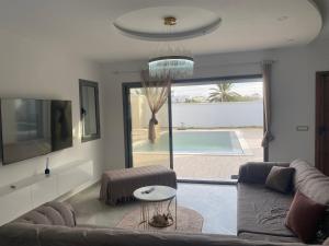 乌姆苏克Villa Oasis Djerba的带沙发的客厅,享有游泳池的景色