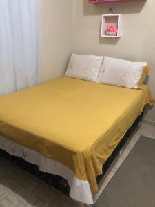 帕林廷斯Aluguel festival de Parintins的一张带黄色床罩和白色枕头的床