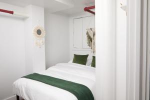 纽约Comfy Guest House in Hell's Kitchen的一间卧室配有带白色床单和绿色枕头的床。