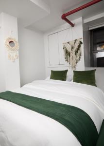 纽约Comfy Guest House in Hell's Kitchen的卧室配有带绿色枕头的大型白色床