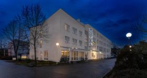 卡尔斯鲁厄PLAZA INN Karlsruhe Nord的白色的建筑,晚上有标志