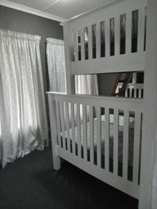 霍维克Howick Greendale 4 Self Catering Units Solar & Battery Back-Up的白色的婴儿床,位于带白色窗帘的房间