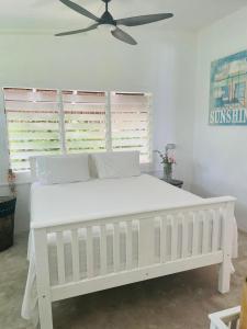EtonBanana Bay Beach Club的卧室内的一张白色床,配有吊扇