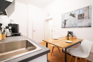 萨勒河畔哈雷Ko-Living - Beatles und Banksy Suites & Studios am Eselsbrunnen - Altstadt - Küche的厨房配有水槽和木桌