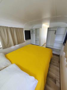 Le Big Bus的小房间,配有床和黄色毯子