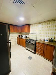 沙迦Sam Home的厨房配有木制橱柜和炉灶烤箱。