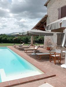 乌尔巴尼亚公爵苑乡村民宿的一座带椅子和遮阳伞的游泳池位于一座建筑旁边