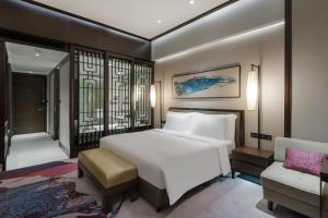 重庆重庆保利花园皇冠假日酒店的卧室配有一张白色大床和一把椅子