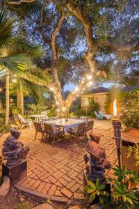 圣巴巴拉Bohemian Art & Garden Cottage Santa Barbara的天井配有桌子,树上配有灯