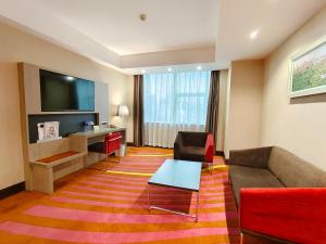 深圳深圳万德诺富特酒店的一间配有沙发、一张桌子和一台电视的酒店客房