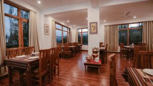 列城Hotel Youthok Heritage的餐厅设有木桌、椅子和窗户。