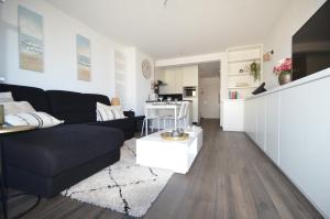 米德尔克尔克An's seaview Middelkerke的一间带黑色沙发的客厅和一间厨房
