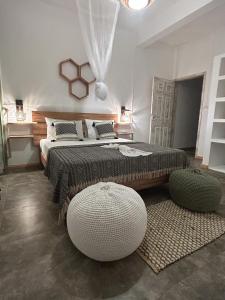 Rodrigues IslandL'oiseau vert apartments的一间卧室配有一张大床和两张搁脚凳