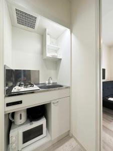 尾道市bHOTEL Yutori - Homestyle 1BR Apartment in Onomichi for 3 Ppl的白色的厨房配有水槽和微波炉