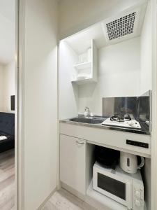尾道市bHOTEL Yutori - Cozy 1Br Apartment for 3Ppl in Onomichi City的白色的厨房配有水槽和微波炉