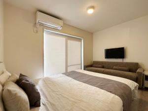 尾道市bHOTEL Yutori - Homestyle 1BR Apartment in Onomichi for 3 Ppl的一间卧室配有一张床、一张沙发和一个窗口