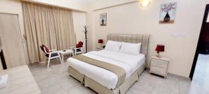 阿尔布亚米Pearl Hotel Apartment - اللؤلؤ للشقق الفندقية的酒店客房带一张床、一张桌子和椅子