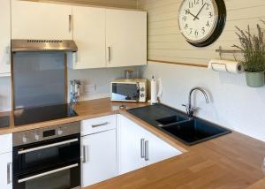 StrattonIvyleaf Combe Lodges的厨房配有水槽和墙上的时钟