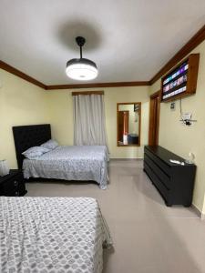 HigueyApartaHotel El Bonao的一间卧室配有两张床和一台平面电视