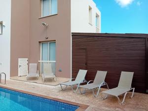 普罗塔拉斯Villa "La Dolce Vita" 3 Bedrooms with pool的一组椅子坐在游泳池旁
