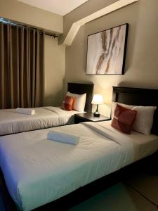 马尼拉G Square Residences的两张位于酒店客房的床,配有两张sidx sidx单人床