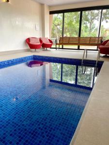 戈亚斯州上帕莱索Pousada Flor de Anis的一个带红色椅子的游泳池,铺有蓝色瓷砖地板