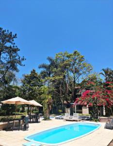 伊皮亚巴斯La Remonta Residence的一个带桌椅的游泳池以及遮阳伞