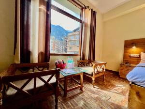 马拉里The Kalinga Resort Manali - Heaven In Mountains的客房设有床、桌子和窗户。