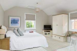 科尔切斯特Stylish and homely 1 bed Edwardian Coach House的白色的卧室设有白色大床和窗户
