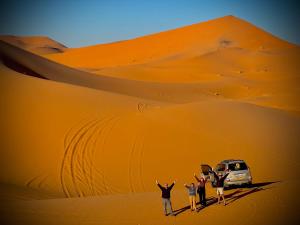 OuzinaPorte De Sahara Ouzina的一群人乘面包车站在沙漠中