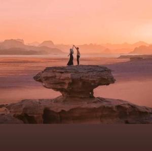 瓦迪拉姆Desert Life Camp的一对夫妇站在海洋的岩石上