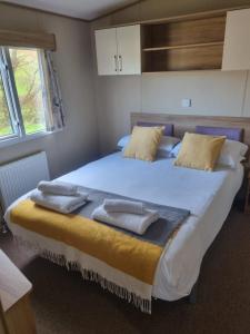 纽基Newquay Bay Porth Caravan - 6 berth的一间卧室配有一张大床和毛巾