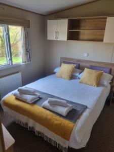 纽基Newquay Bay Porth Caravan - 6 berth的一间卧室配有一张大床和两条毛巾