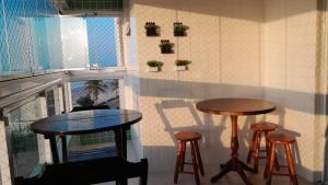 蒙加瓜Belíssimo apartamento frente mar的带窗户的房间里有两个桌子和凳子