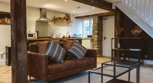 切普斯托Gardener's Cottage的一间带棕色沙发的客厅和一间厨房