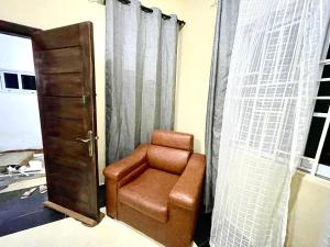 阿克拉Accra Luxury Apartments At The Sanga Estates的棕色椅子,坐在带窗帘的房间
