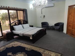 白沙瓦Askari Gold Crest的一间卧室配有一张床、两把椅子和一个吊灯