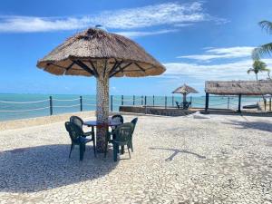 马拉戈日Village Gales Prive Maragogi的海滩上草伞下的桌椅