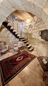 格雷梅Chelebi Cave House Hotel Over 6的一间带两把椅子和楼梯的客厅