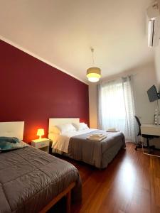 罗马Lucens Domus Appartamento Roma quartiere Trieste - vicino Metro b1 -的一间卧室设有两张床和红色的墙壁