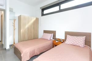 古尔内斯Nikolas Villa的带窗户的客房内的两张床和粉红色的床单