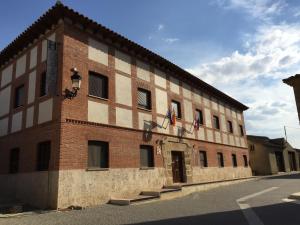 Boadilla del CaminoHotel Rural En El Camino的一座大砖砌建筑,上面有两面旗帜