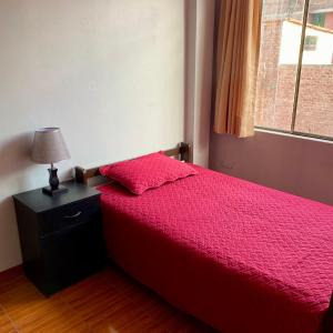 阿亚库乔Duplex amoblado en el corazón de Ayacucho的一间卧室配有红色的床、灯和窗户