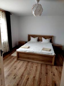 布泽乌Casuta de sub munte的一间卧室配有一张铺有木地板的白色床单。